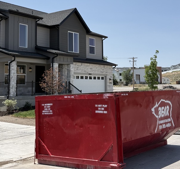 A red Bear Services dumpster parked outside a newly built home